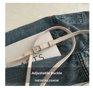 Detail of adjustable off-white pebble leather strap with silver buckle and fine stitching