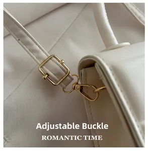 Macro shot of gold-tone adjustable buckle and lobster clasp on cream leather handbag strap