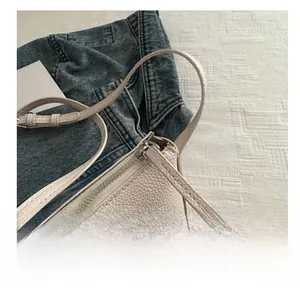 Close-up of smooth metal zipper and pebbled leather texture on beige bucket bag