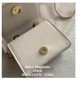 Detail view of gold magnetic hardware closure on beige PU leather crossbody bag