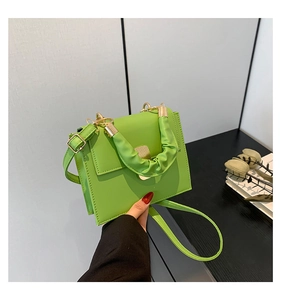 Detail of light green faux leather crossbody bag with pleated handle and gold hardware