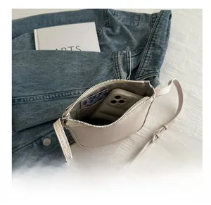 Detail view of cream leather crossbody bag interior showing phone and card storage capacity