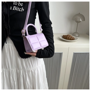 Detail of purple quilted PU leather handbag with woven handle and adjustable strap