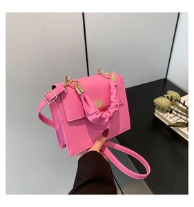 Detailed shot of pink square handbag featuring a stylish ruffled handle and gold metal snap