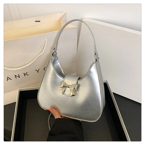 Dettaglio borsa a mano argento metallizzato con chiusura a fiocco e tracolla chic
