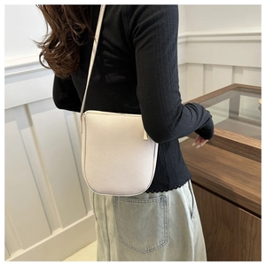 Detail of cream lychee grain leather crossbody bag showing texture and saddle shape