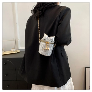 Détail du sac seau argenté avec matelassage cœur et nœud 3D sur un blazer