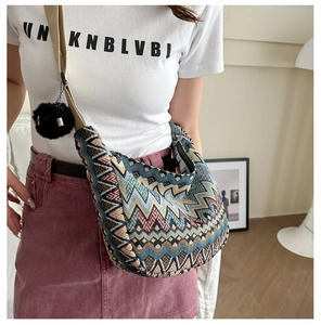 Détail du sac hobo tissé avec motifs de vagues colorés et pendentif en peluche noire