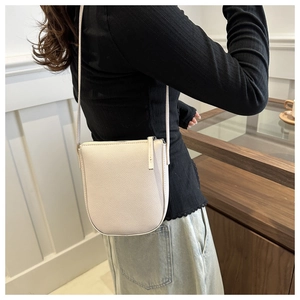 Off-white pebbled leather crossbody bag worn by a model in a minimalist interior setting