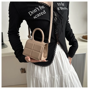 Detail of beige quilted PU leather handbag with embossed grid design and round handle