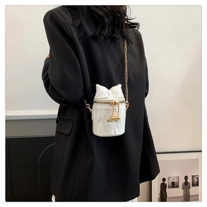 Vue arrière d'un mini sac cylindre blanc avec nœud et chaîne dorée sur un mannequin
