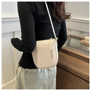 Detail of off-white lychee grain leather crossbody bag shown on model in home setting
