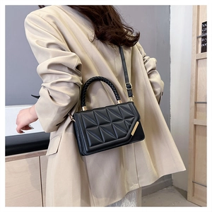 Detail der schwarzen Stepptasche mit geflochtenem Griff und goldenen Beschlägen
