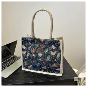 Detailopname van vintage canvas lunchtas met kleurrijke vlinderpatronen en linnen handvatten