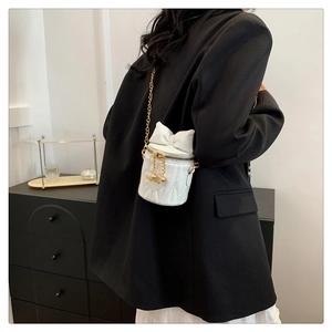 Détail du mini sac seau blanc avec matelassage en cœur et grand nœud décoratif