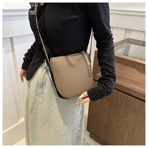 Detail of taupe litchi grain leather crossbody bag showing the premium metal zipper