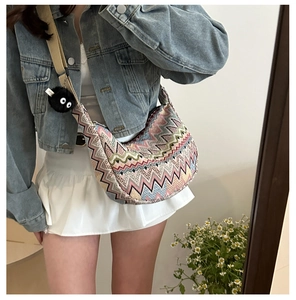 Détail du sac tricoté en zigzag coloré avec large bandoulière et pendentif peluche