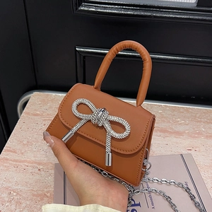 Brown mini handbag with sparkling rhinestone bow and chain strap in luxury setting