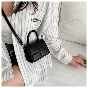 Detail of black quilted leather crossbody bag worn by a model in a casual setting