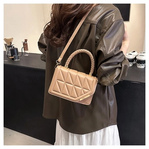 Vue détaillée du sac à main matelassé beige avec poignée tressée dans un café chic