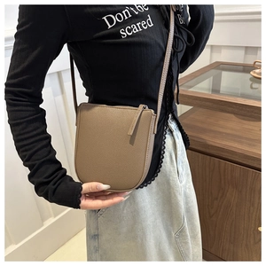 Detail of khaki pebbled leather crossbody phone bag shown on a model for actual size reference
