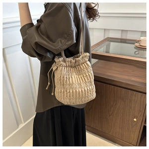 Détail d'un sac seau plissé beige en similicuir avec cordon et fine bandoulière réglable