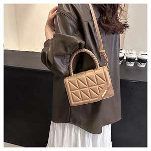 Quilted khaki crossbody bag with gold detail and woven handle shown in a lifestyle setting