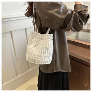 Détail du sac seau blanc plissé avec texture fine et fine bandoulière élégante