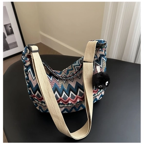 Détail du sac cabas tissé coloré avec une large bandoulière et un charme en peluche