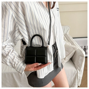 Detail of black quilted mini square handbag with gold hardware and top handle for women