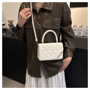 Weiße Stepptasche mit geflochtenem Griff an Model in stilvoller Café-Atmosphäre gezeigt
