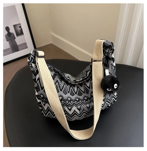 Détail du sac en toile tissée à motifs géométriques avec un pendentif noir en peluche douce
