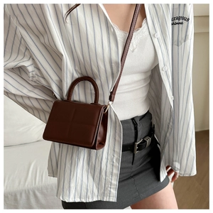 Detail of dark brown PU leather handbag showing cross-stitch flap and adjustable strap