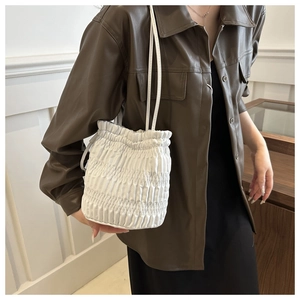 Détail du sac seau plissé blanc avec cordon de serrage porté à l'épaule par le mannequin