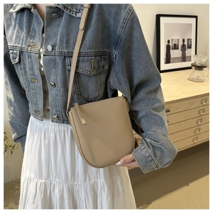 Detail of khaki pebbled leather crossbody bucket bag with zipper and stitching textures
