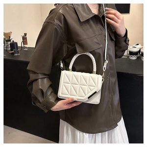 Détail du sac à main matelassé blanc crème avec poignée tressée porté par un mannequin