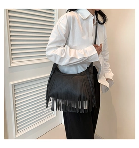 Sac à bandoulière noir à franges stylé, porté avec chemise blanche et pantalon noir chic