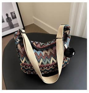 Détail du sac bandoulière en tricot coloré avec motif zigzag et breloque pompon noir