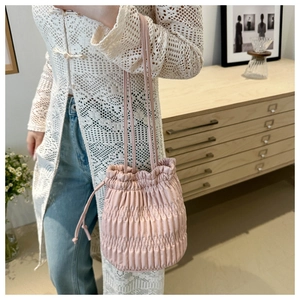 Vue détaillée du sac seau rose à cordon avec texture plissée élégante et bandoulière