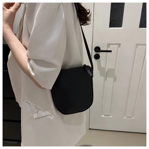Close-up of black lychee-textured crossbody bag shown on model in indoor setting