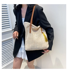 Detail of woven straw tote bag with V-shaped knit pattern and brown leather straps