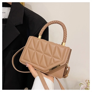 Detail von geflochtenem Griff und Steppmuster auf hellbrauner modischer Handtasche