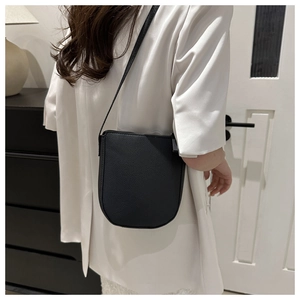 Detail of the black pebbled leather texture and U-shaped design on the crossbody bucket bag