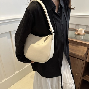 Chic cream hobo shoulder bag with pebble grain texture shown on a stylish model