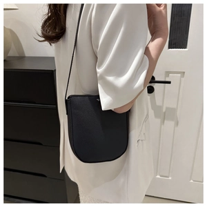Minimalist black lychee texture saddle crossbody bag styled with a white blazer outfit