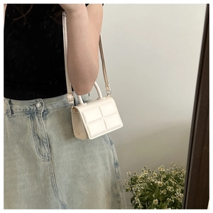 Close-up of cream white quilted PU leather handbag with elegant top handle and strap