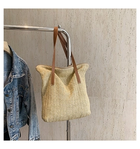 Détail de la texture en paille tressée en V et de la bandoulière en cuir marron du sac