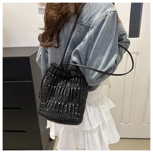 Détail du sac seau noir plissé avec fermeture à cordon porté par un mannequin