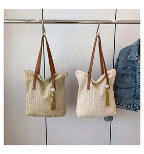 Détail de sacs cabas en paille beige et naturelle avec bandoulières en cuir marron