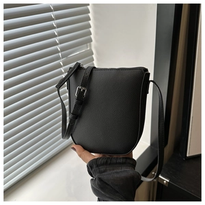 Close-up of black lychee texture crossbody bag featuring a curved base and silver hardware